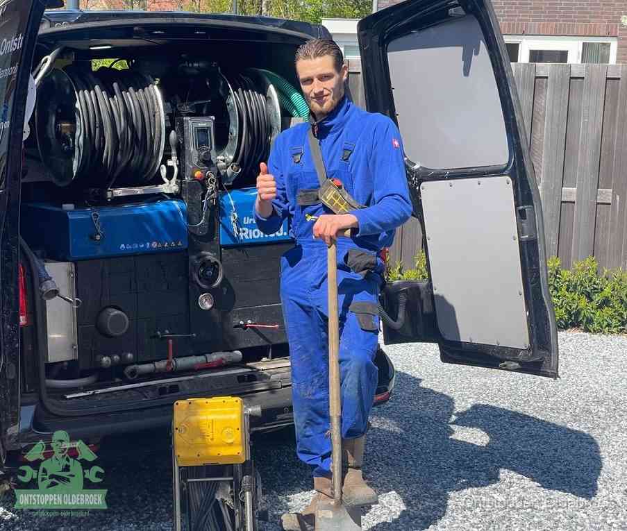Een monteur bij de werkbus met grote hogedruk-slanghaspels, apparatuur voor hardnekkige afvoerverstoppingen in Oldebroek