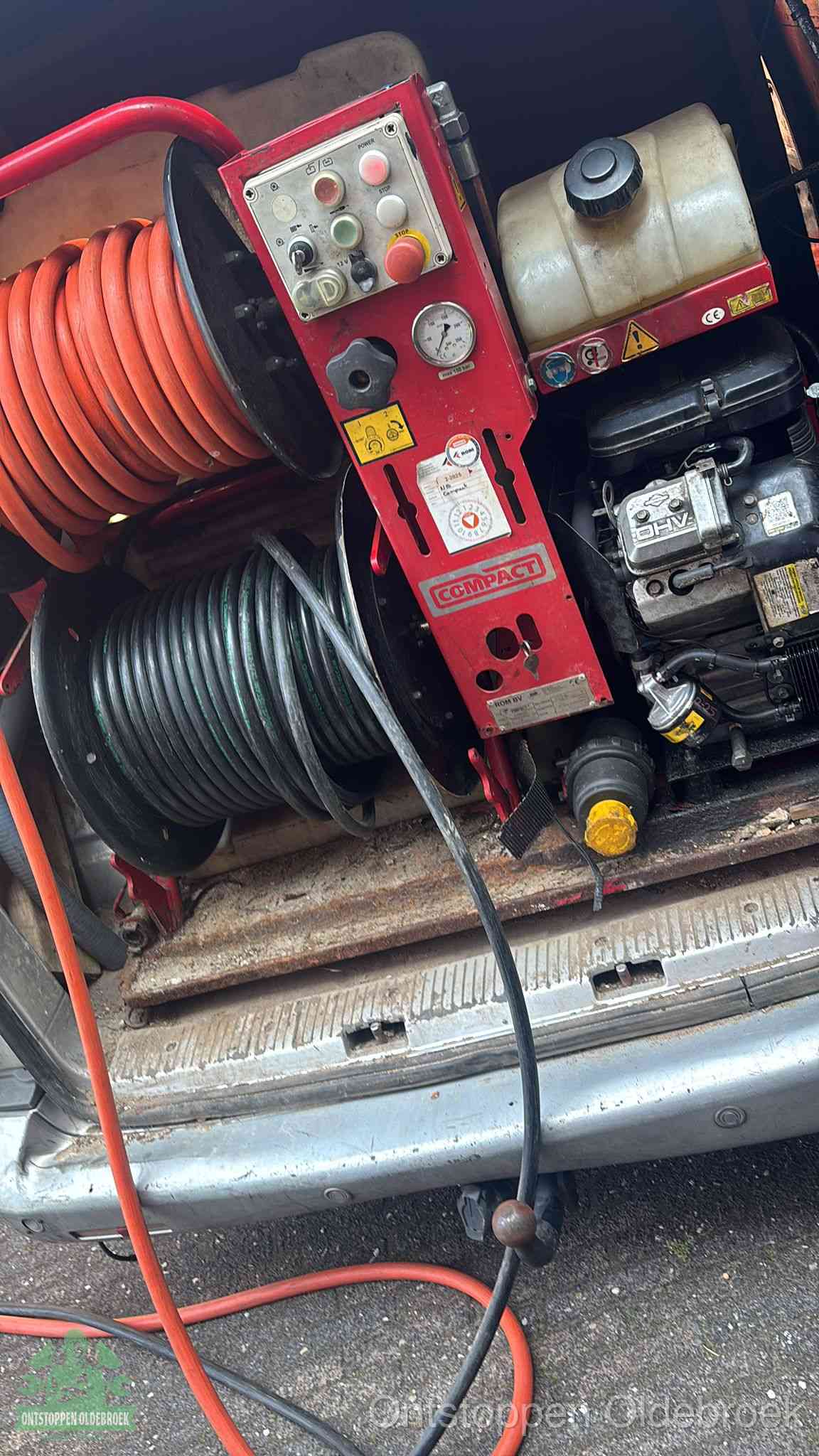 Een rood hogedruk-rioolreinigingstoestel met slangen in de laadbak van de bedrijfsbus, apparatuur voor een hardnekkige wc-verstopping in Oldebroek