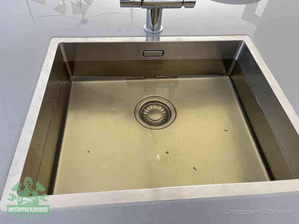 Stilstaand water in een rvs spoelbak dat niet wegloopt, een duidelijk signaal van een gootsteenverstopping in Oldebroek