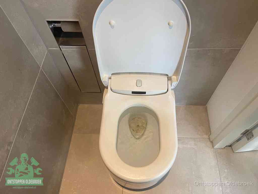 Een wit hangtoilet waarin een prop wc-papier op het water blijft drijven, een duidelijk signaal van een verstopte wc in Oldebroek