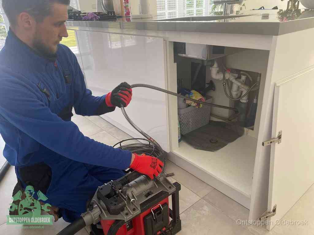 Een monteur reinigt de keukenafvoer grondig met een veermachine om terugkerende gootsteenverstoppingen te voorkomen in Oldebroek