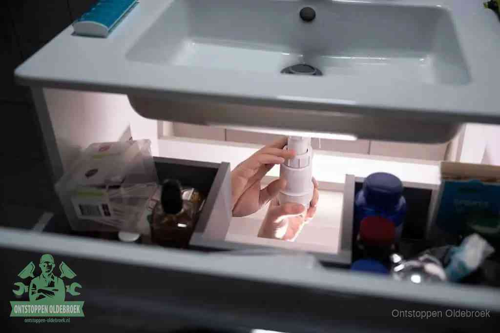 Een pompfles met zeep boven een wastafel in de toiletruimte, de warm water en afwasmiddel-methode om de wc te ontstoppen in Oldebroek