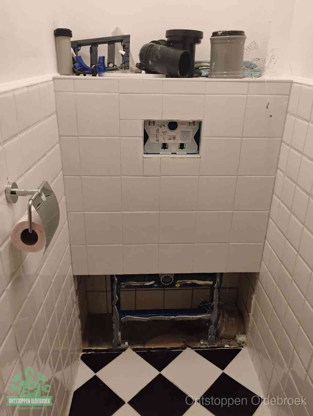 Een toiletruimte waar het hangtoilet en de inbouwreservoir-onderdelen zijn vrijgelegd voor onderhoud, periodiek nazicht voorkomt een wc-verstopping in Oldebroek